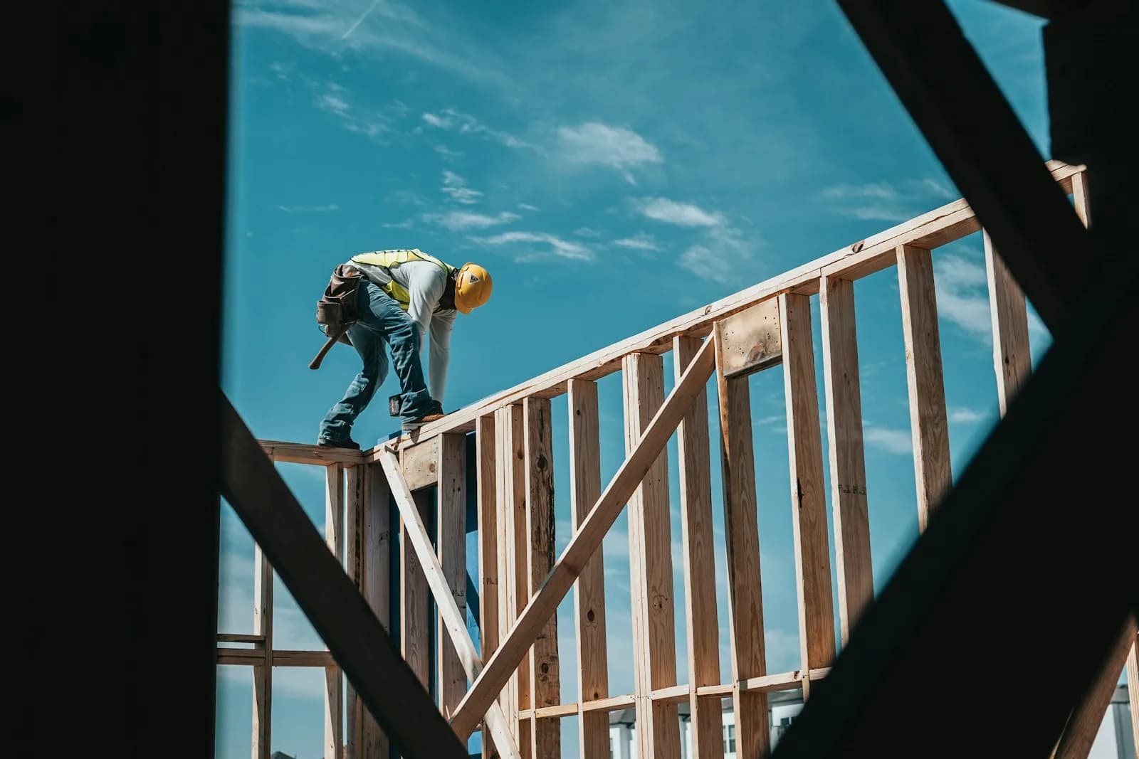 A framer working on top of a wood-framed wall